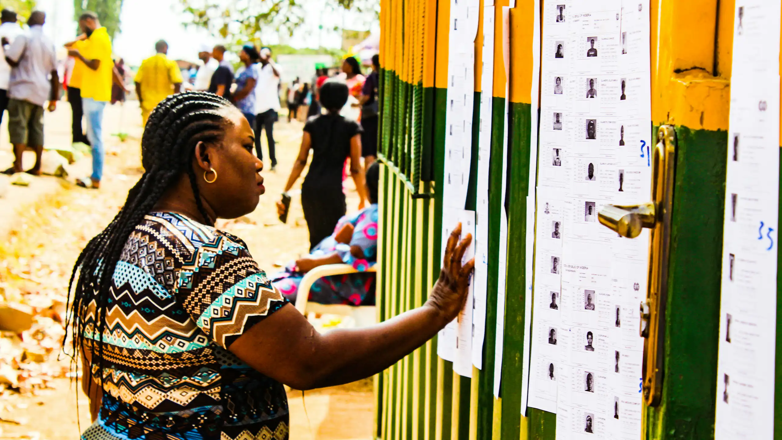A woman looking at a list of names pasted on a multicoloured wall