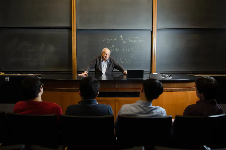 Un homme âgé enseigne devant une classe