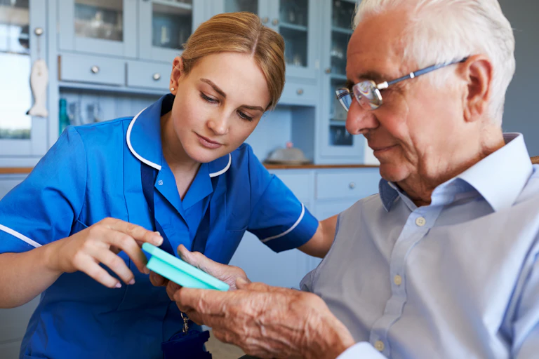 A female carer helps an elderly man with his prescription.