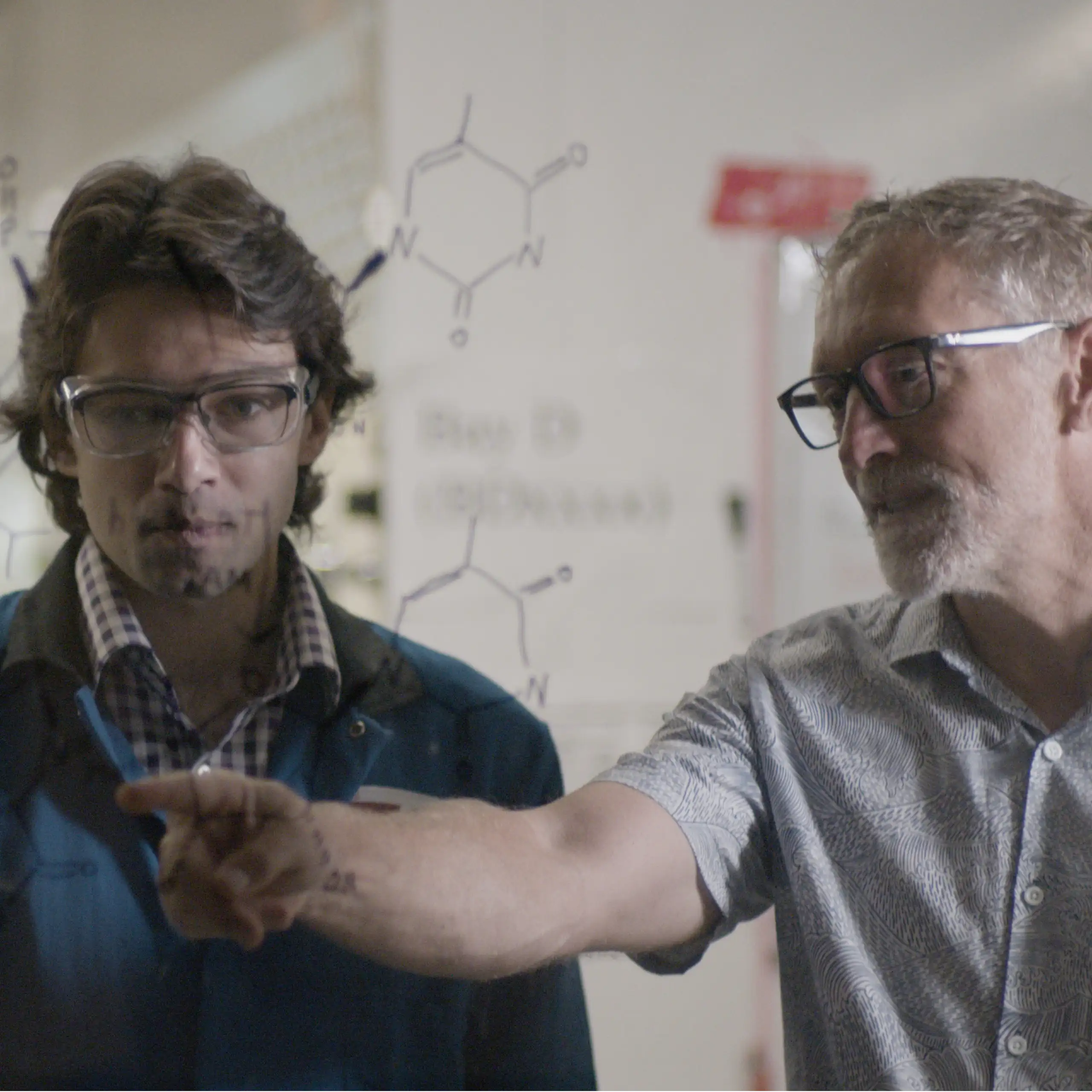 Three scientists discussing chemical drawings