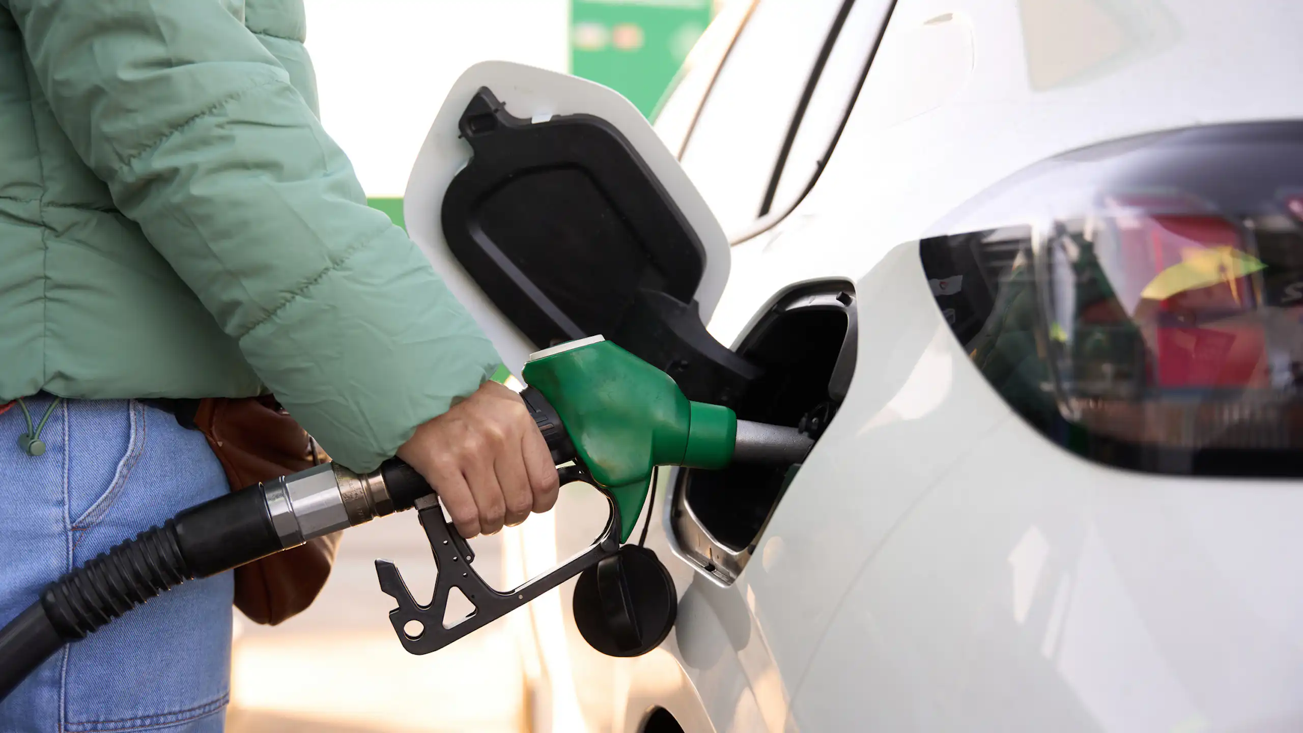 Close-up view of a woman pumping petrol into a car.