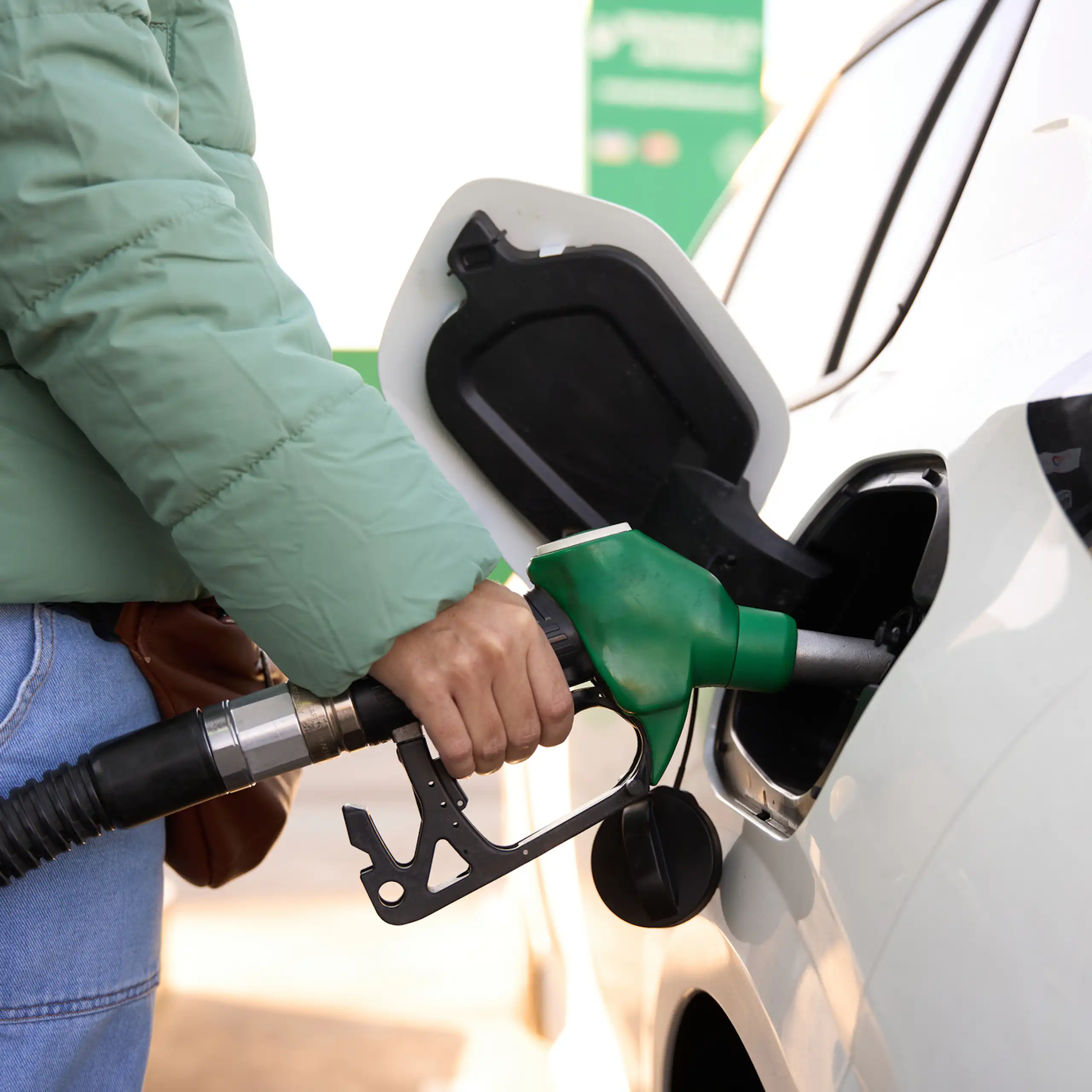 Close-up view of a woman pumping petrol into a car.