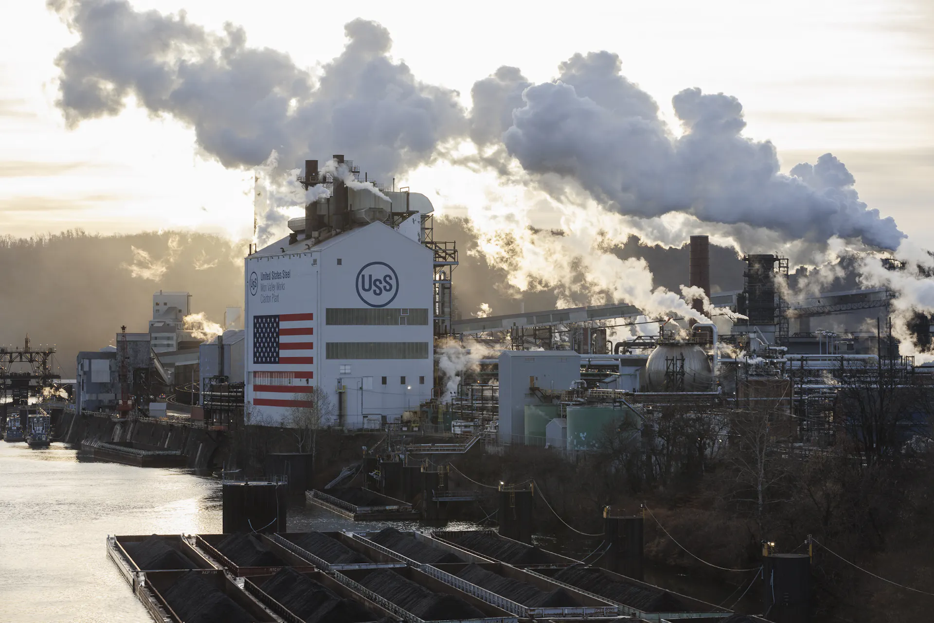 A large industrial building complex sits alongside a river.