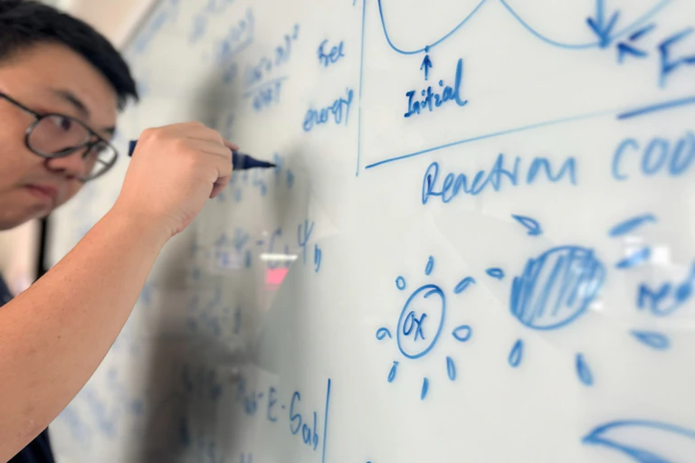 Un étudiant écrit des équations sur un tableau