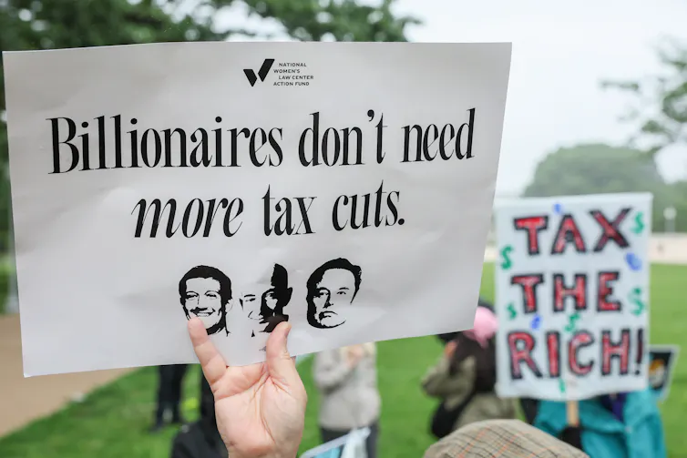 Demonstrators hold up signs during a rally opposing House Republicans Tax Proposa