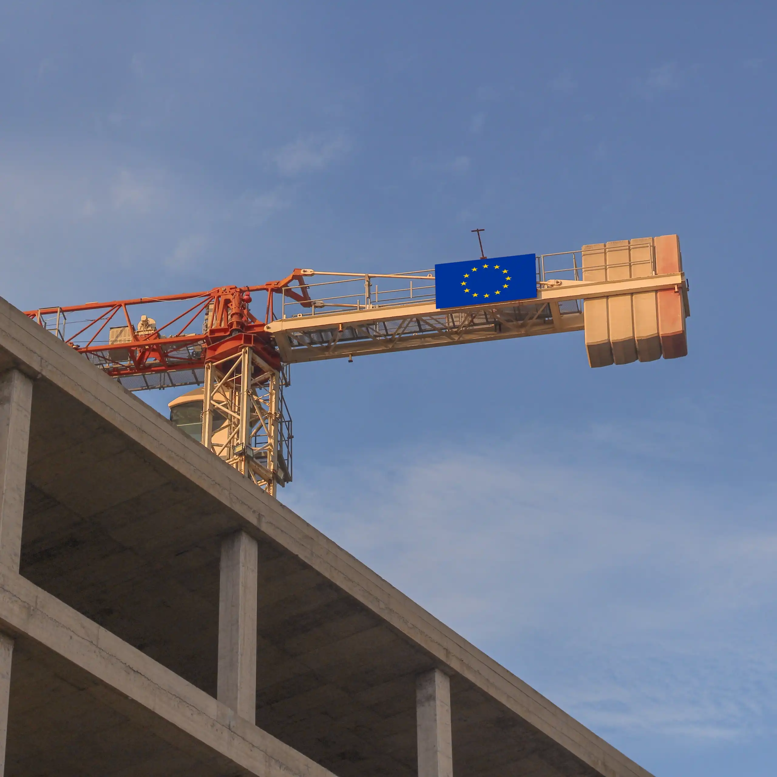Grue avec un drapeau européen devant un bâtiment.