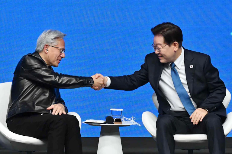 Lee Jae Myung and Jensen Huang shake hands while speaking at a summit.