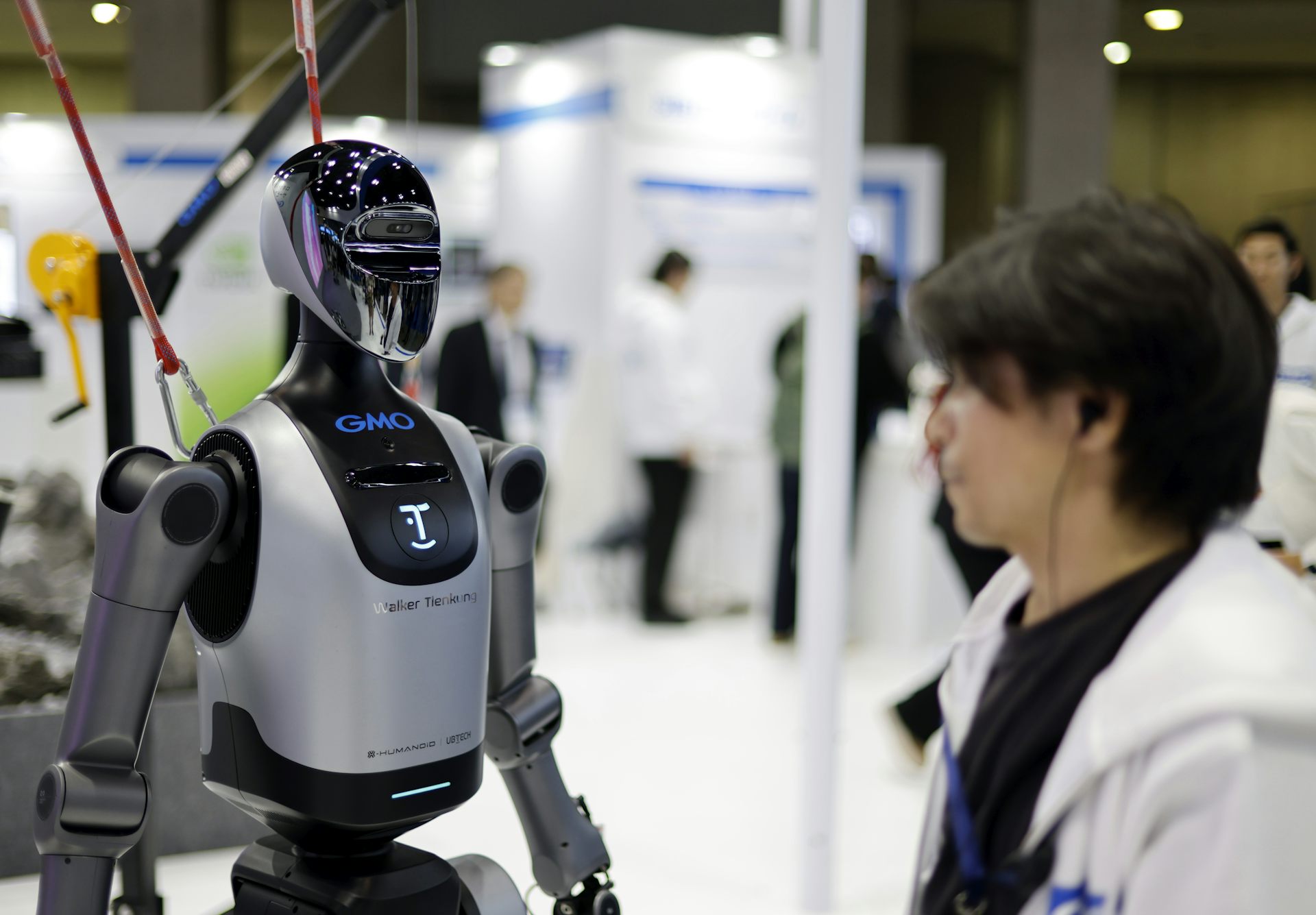 A staff member stands next to a humanoid robot during an exhibition in Tokyo.