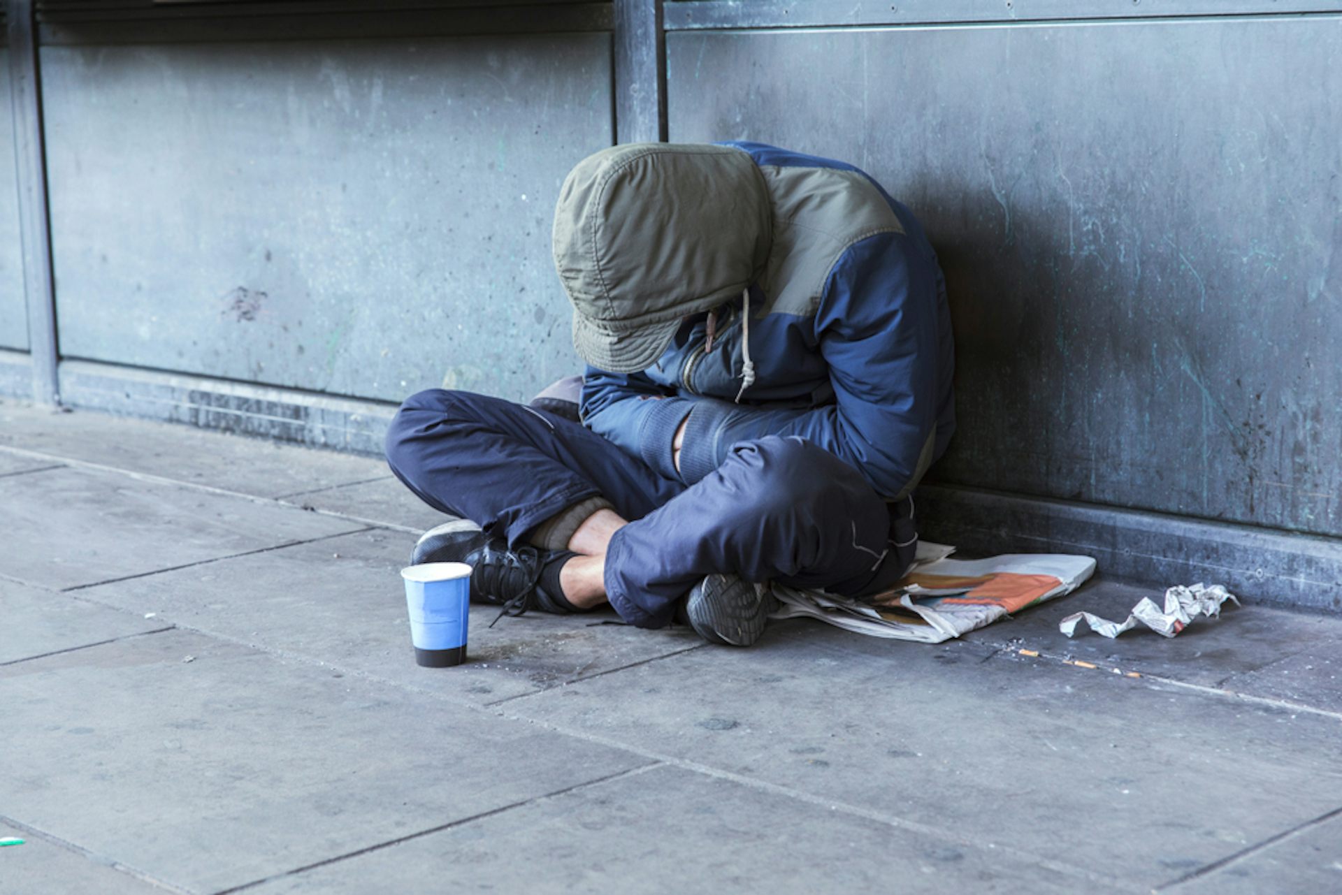 Man sitting on a pavement, his head bowed.