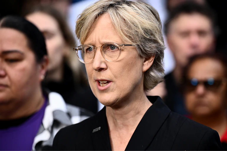 A woman in glasses speaking to media