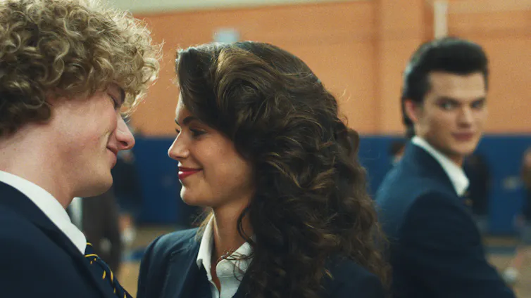 a boy and girl smile at each other, while another boy looks on longingly