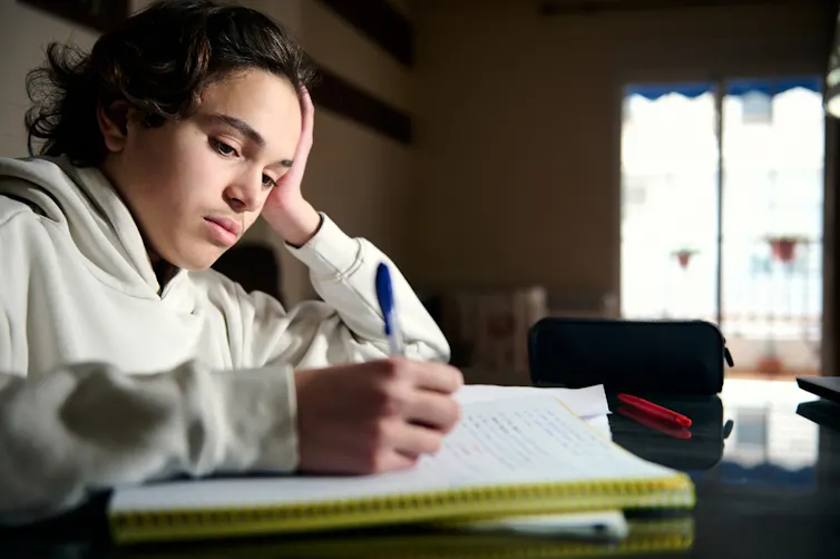 Un adolescent écrit dans un cahier