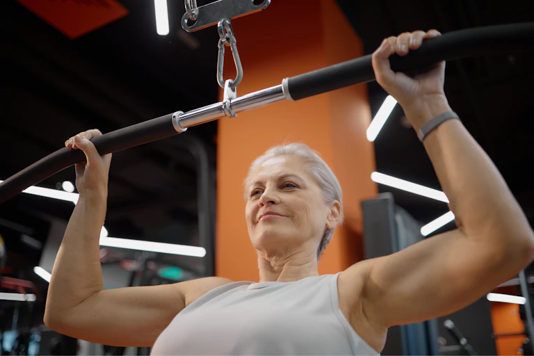 Una mujer en un gimnasio hace ejercicios de fuerza con un aparato