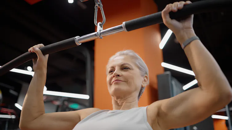Una mujer en un gimnasio hace ejercicios de fuerza con un aparato