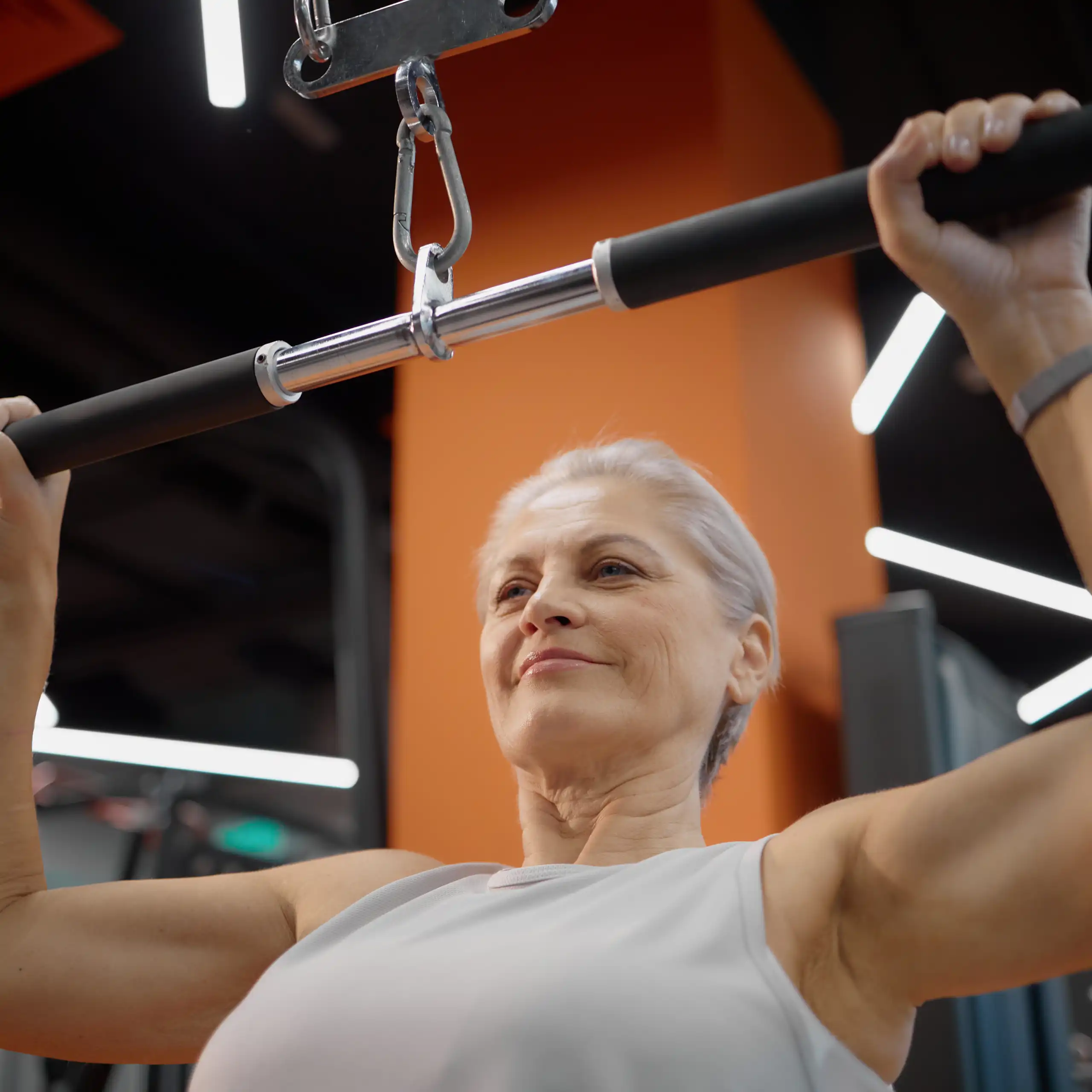Una mujer en un gimnasio hace ejercicios de fuerza con un aparato
