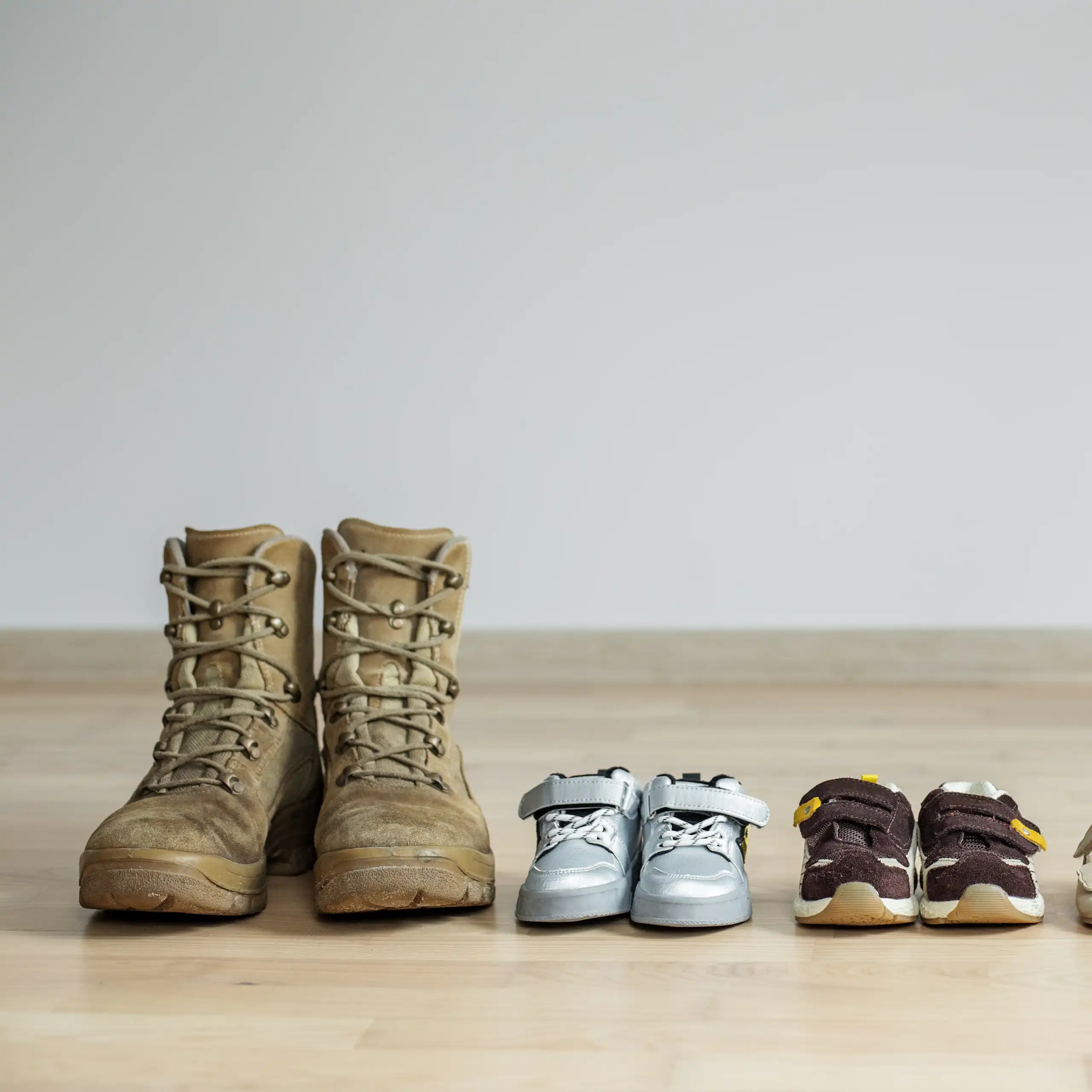 Une paire de chaussures d'adulte est alignée avec des paires d'enfants de plus en plus petites.