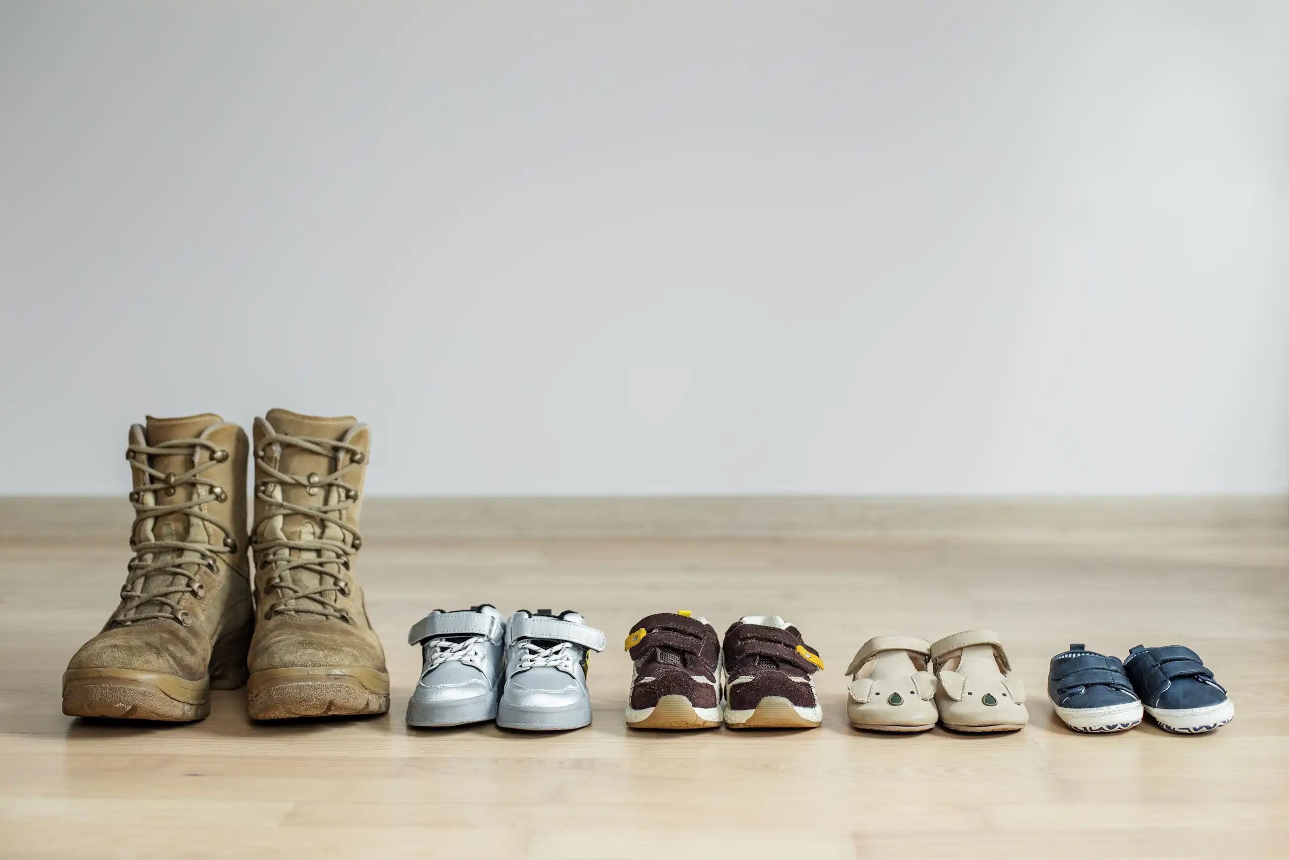 Une paire de chaussures d'adulte est alignée avec des paires d'enfants de plus en plus petites.