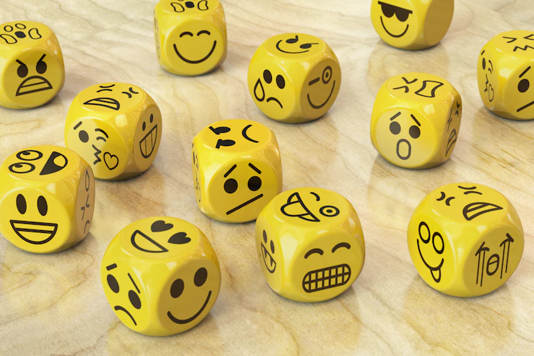 Scattered yellow dice with painted emojis on each face