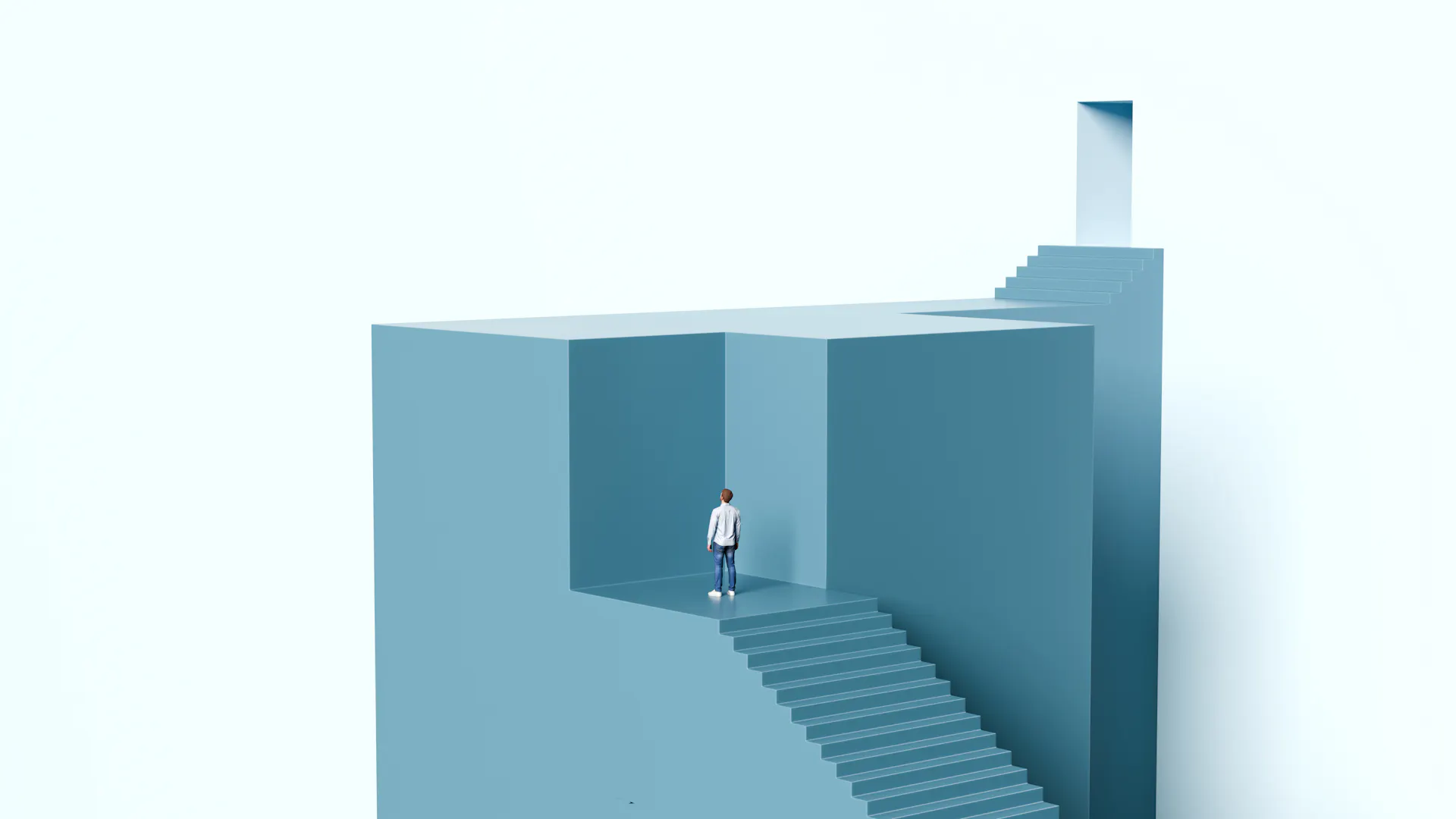 Man standing at the top of a staircase blocked by a solid wall looking toward a door located above him.