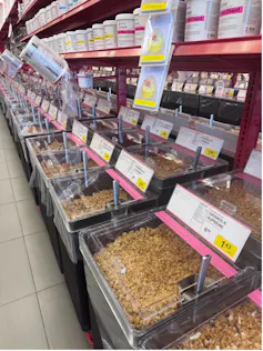 A store aisle containing several bins filled with food items, with scoops to scoop them out.