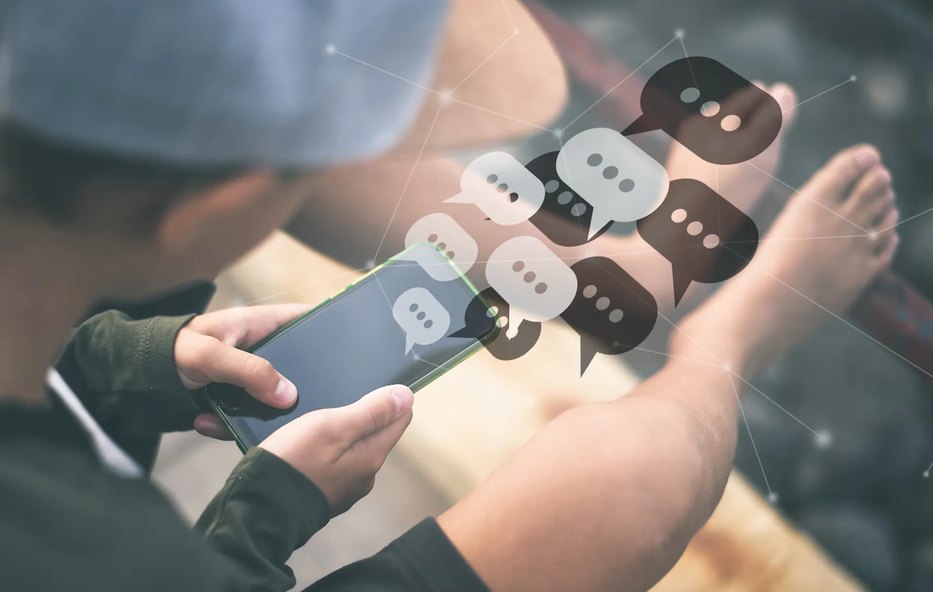 A boy looking down at a phone, with cartoonish chat icons on top of the phone.
