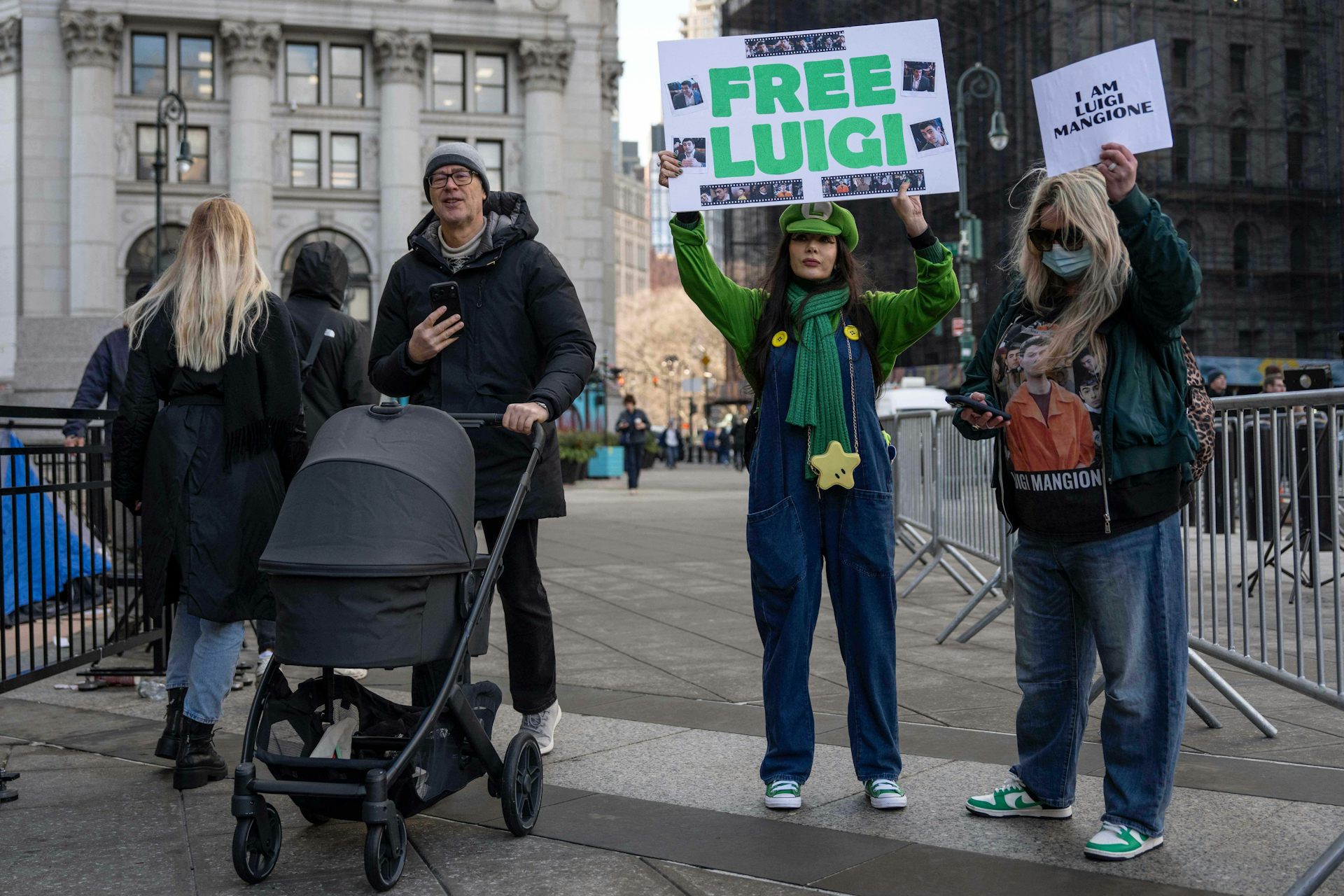 One person dressed in a green Luigi costume holds a 'FREE LUIGI' sign, while another holds a sign reading 'I AM LUIGI MANGIONE.'