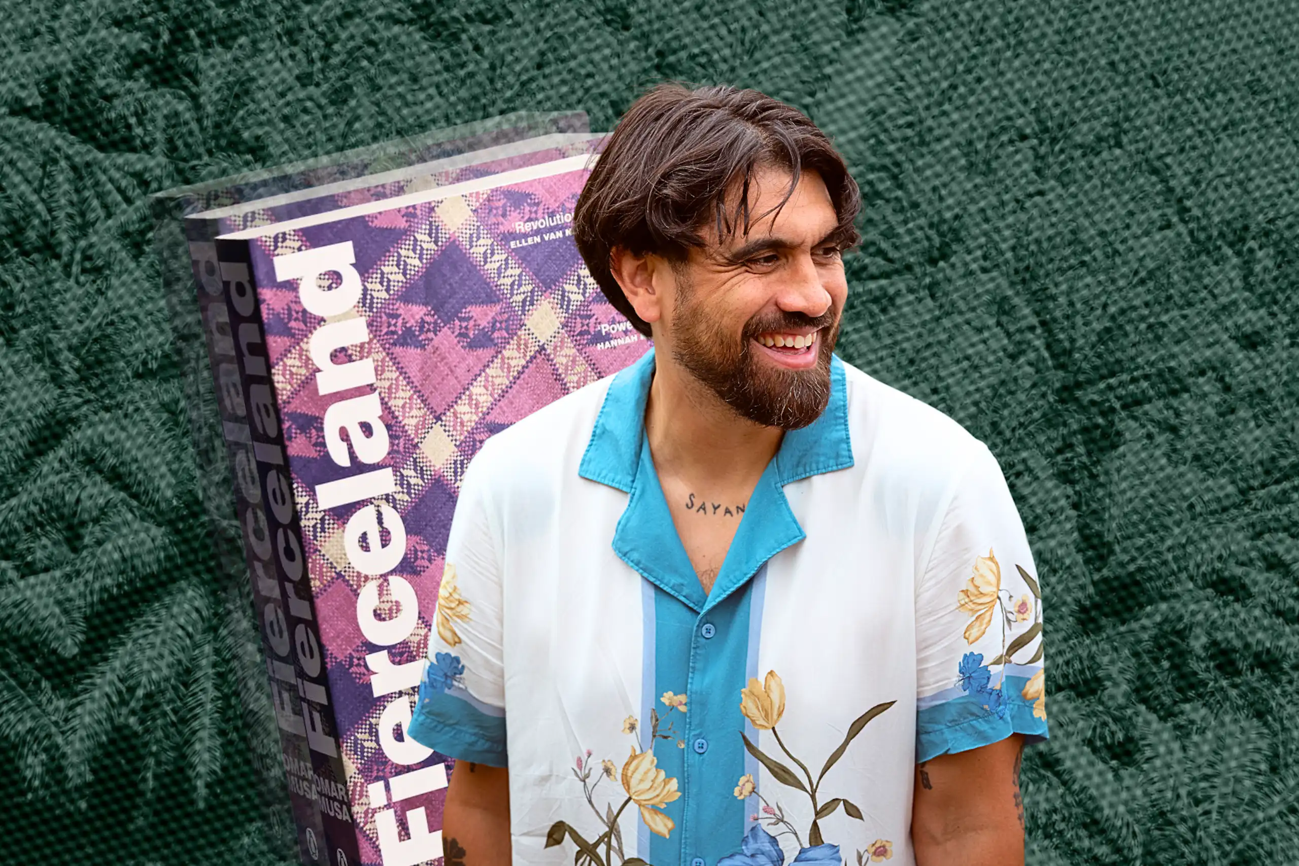 a smiling bearded man in a white shirt with flowers