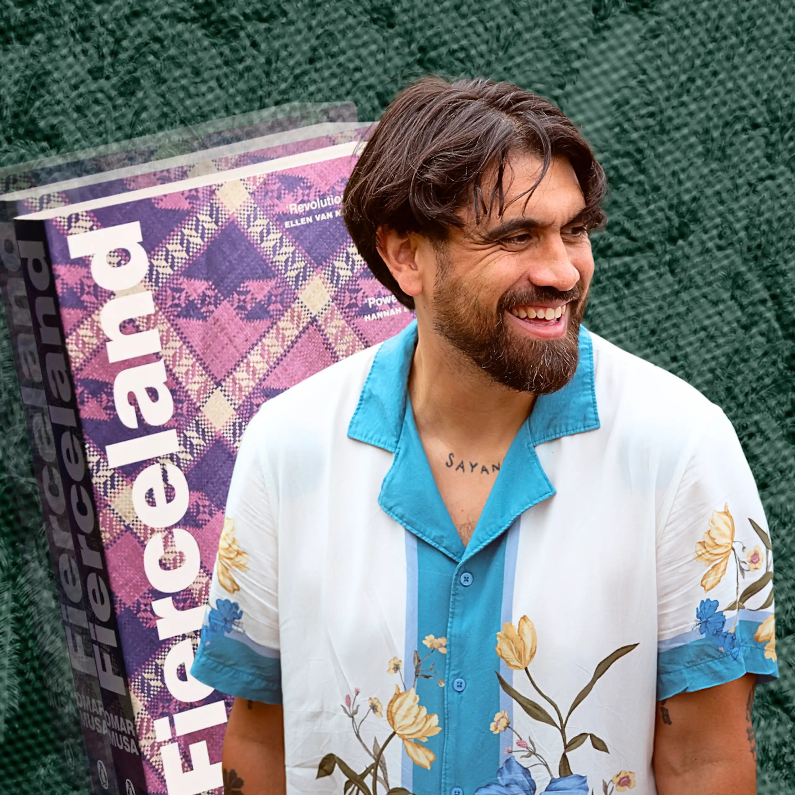 a smiling bearded man in a white shirt with flowers