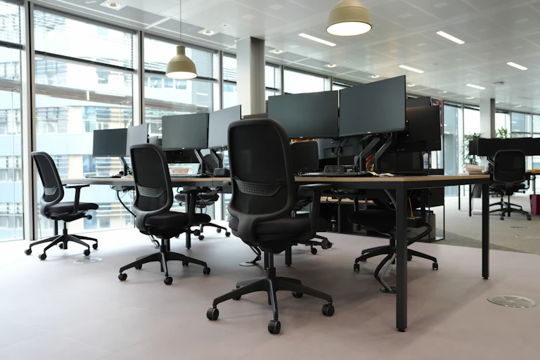 Generic stock view of an empty office with desk and chairs and monitors.