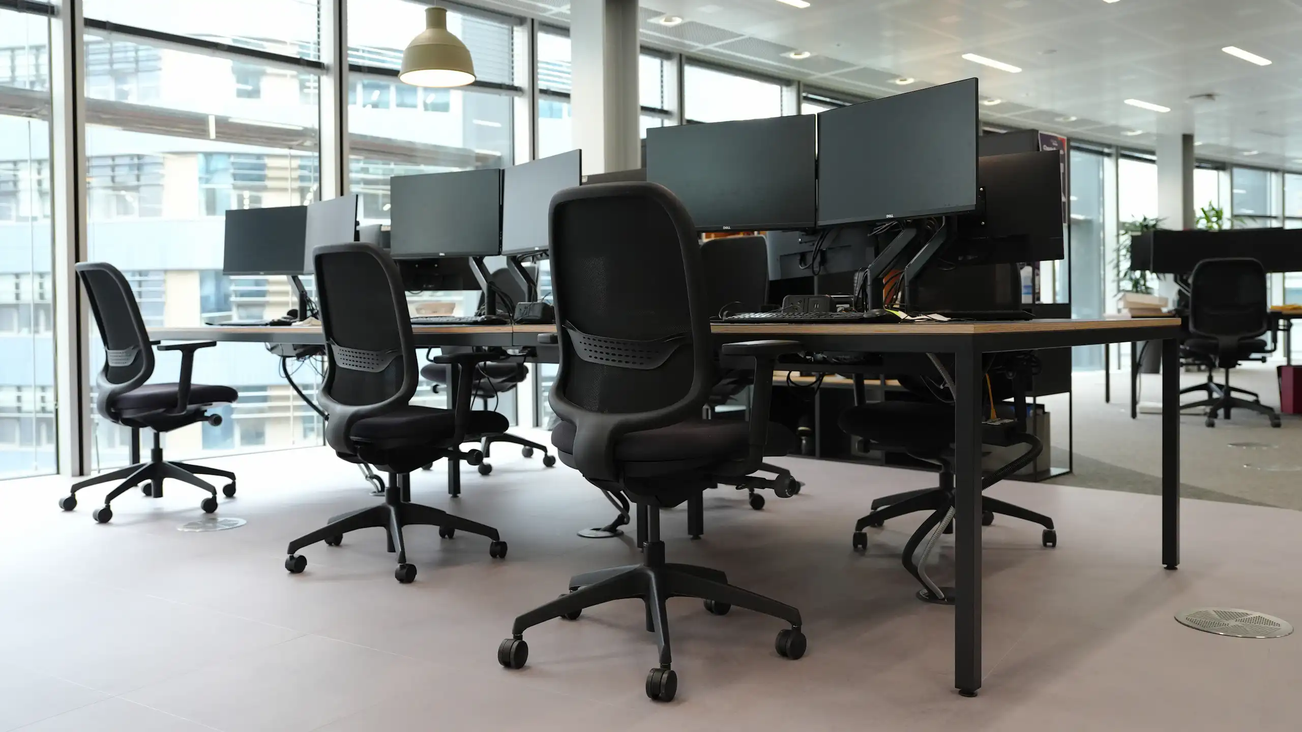 Generic stock view of an empty office with desk and chairs and monitors.