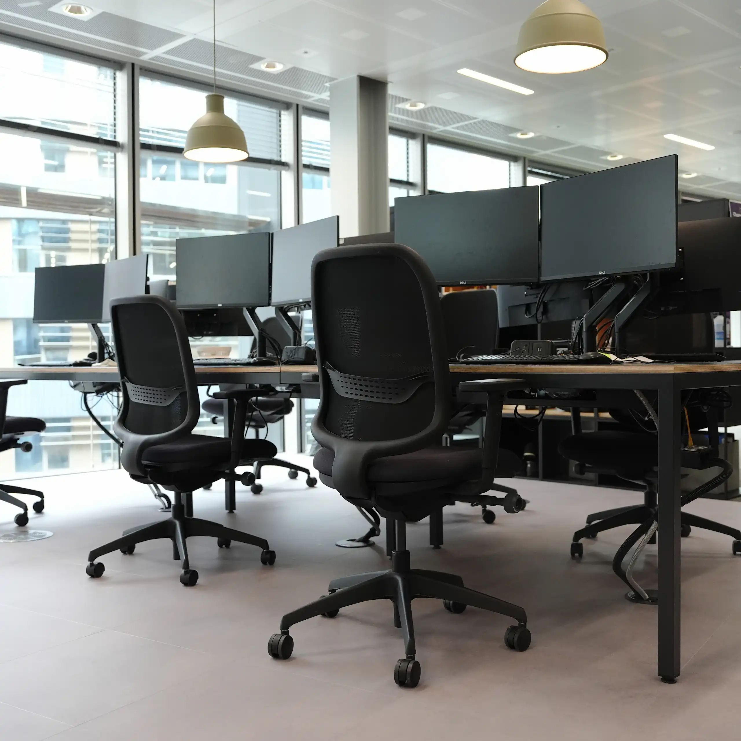 Generic stock view of an empty office with desk and chairs and monitors.