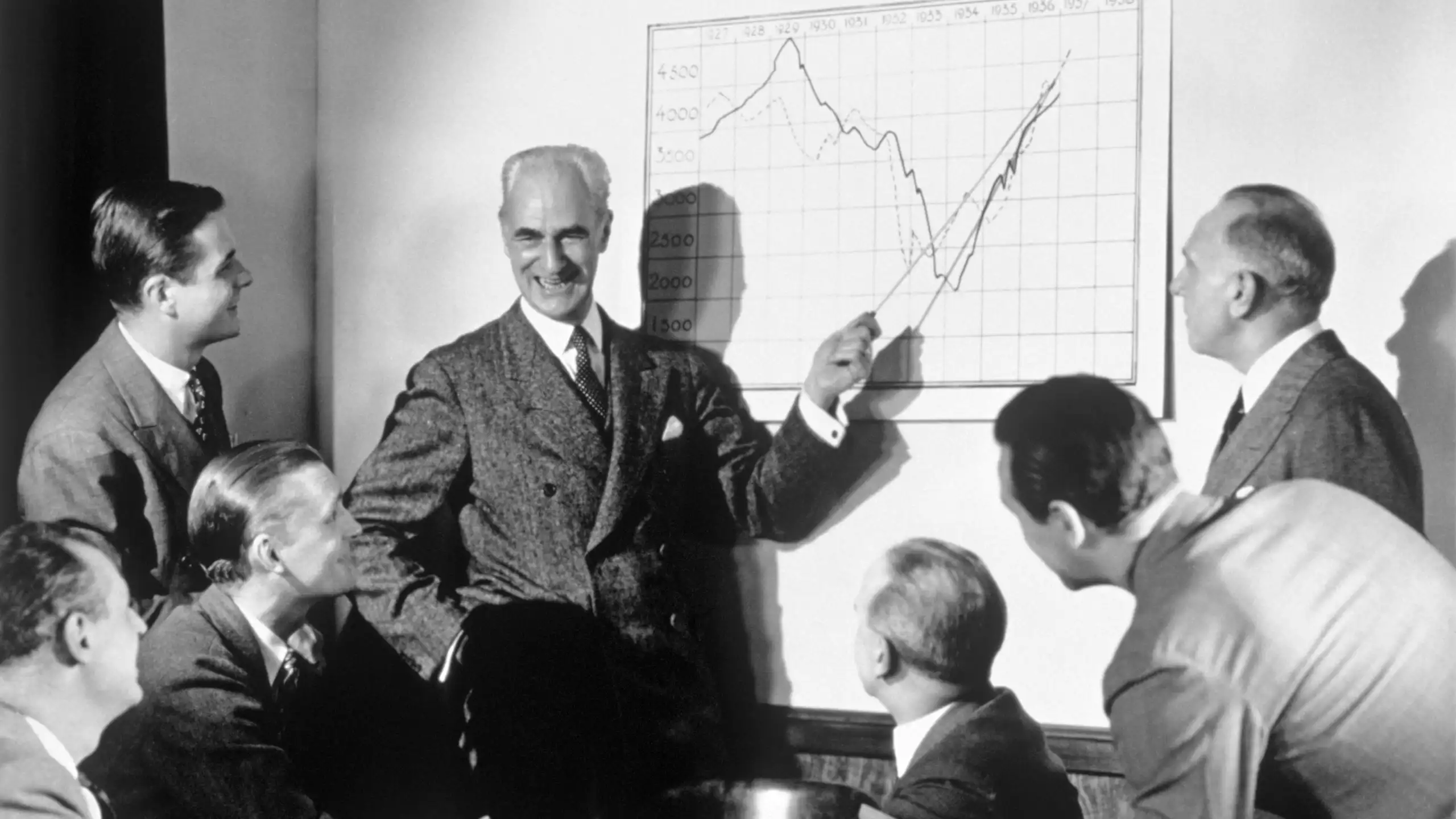 A group of businessmen laughing while looking at a chart
