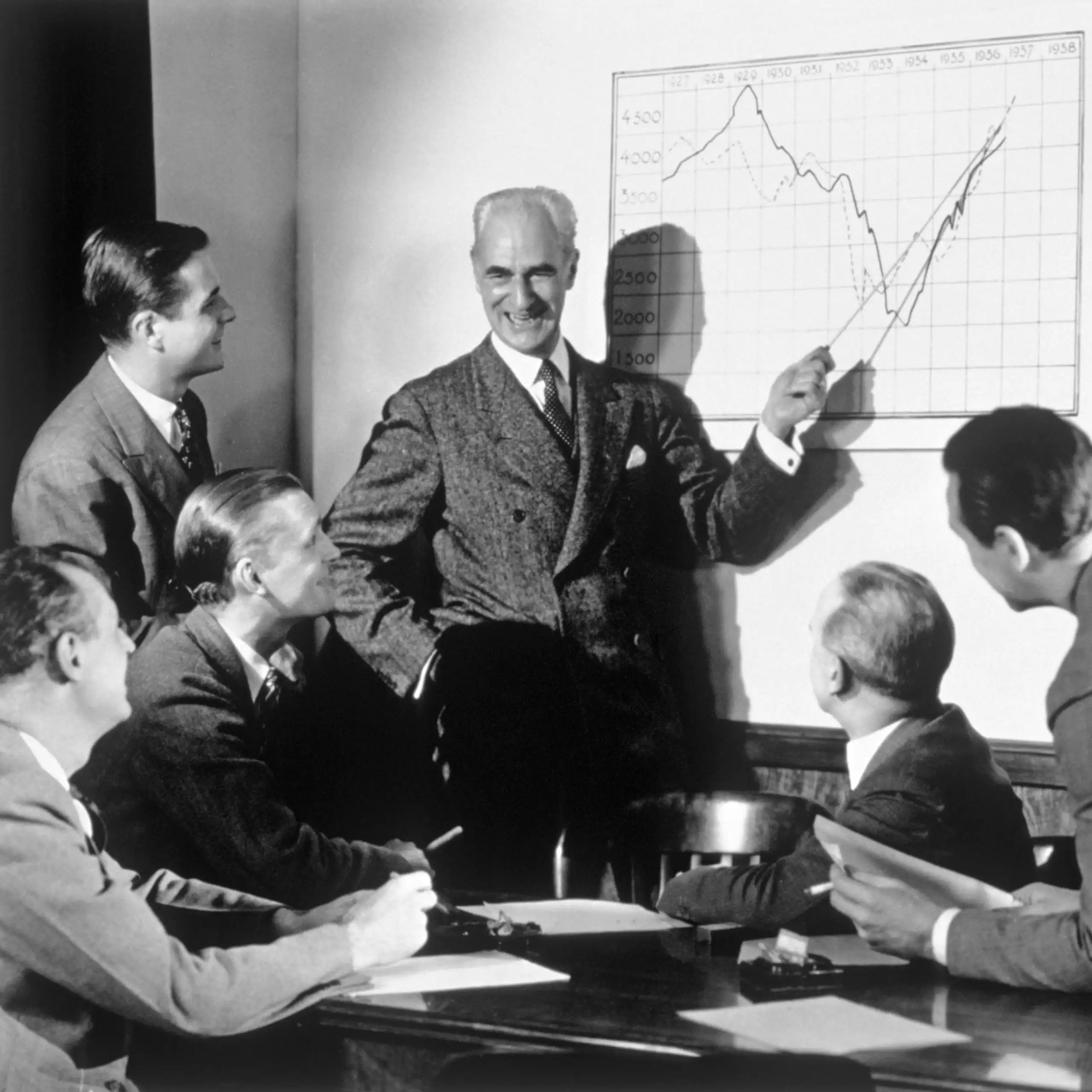 A group of businessmen laughing while looking at a chart