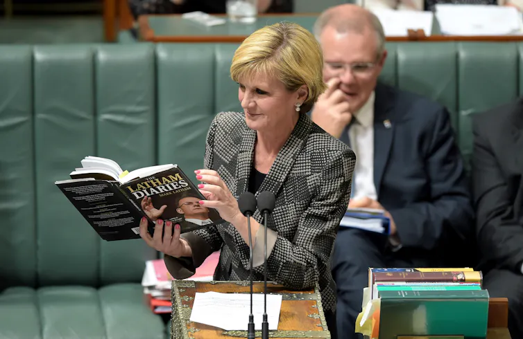 a woman reading a book, a man behind her on a bench