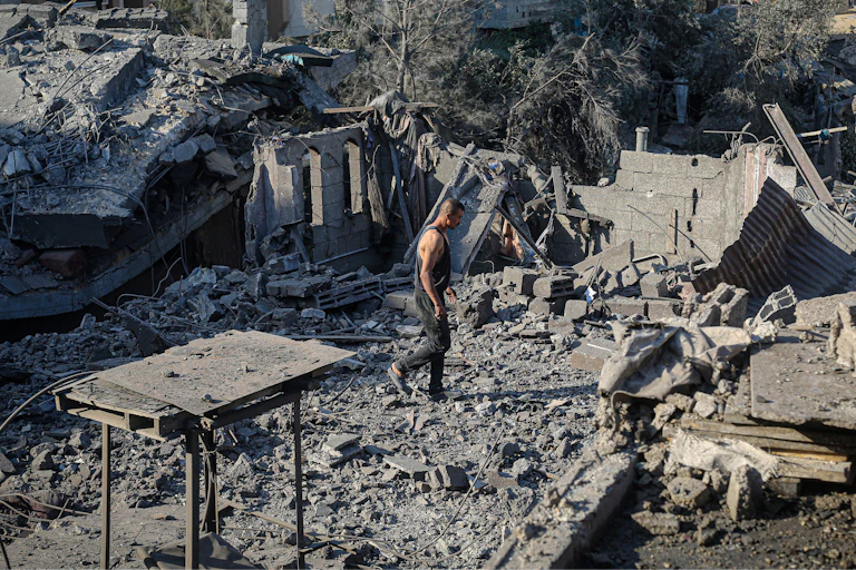 A man walks around rubble.