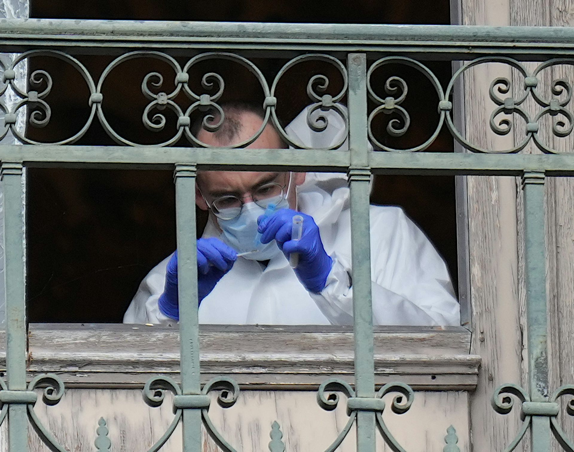A Paris Police crime scene technician collects DNA evidence from a missing window frame that was cut open by thieves during the Louvre heist.