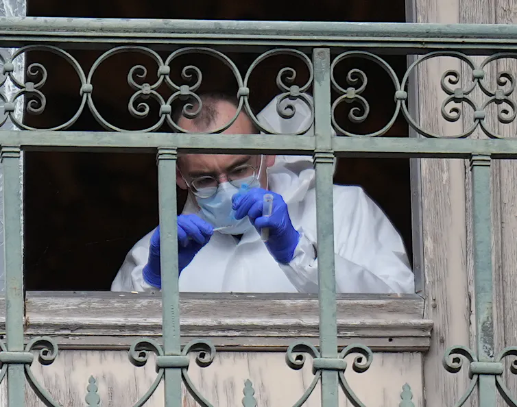 A Paris Police crime scene technician collects DNA evidence from a missing window frame that was cut open by thieves during the Louvre heist.