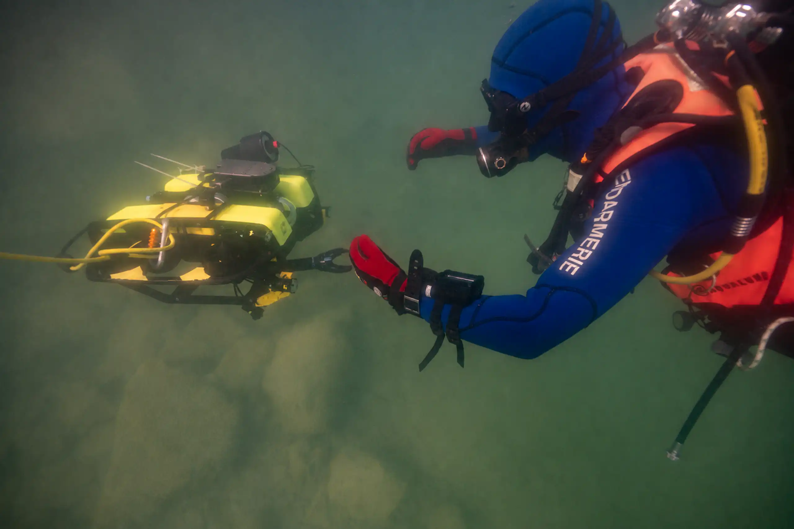 Prise de vue sous l'eau d'un agent manipulant le ROV.