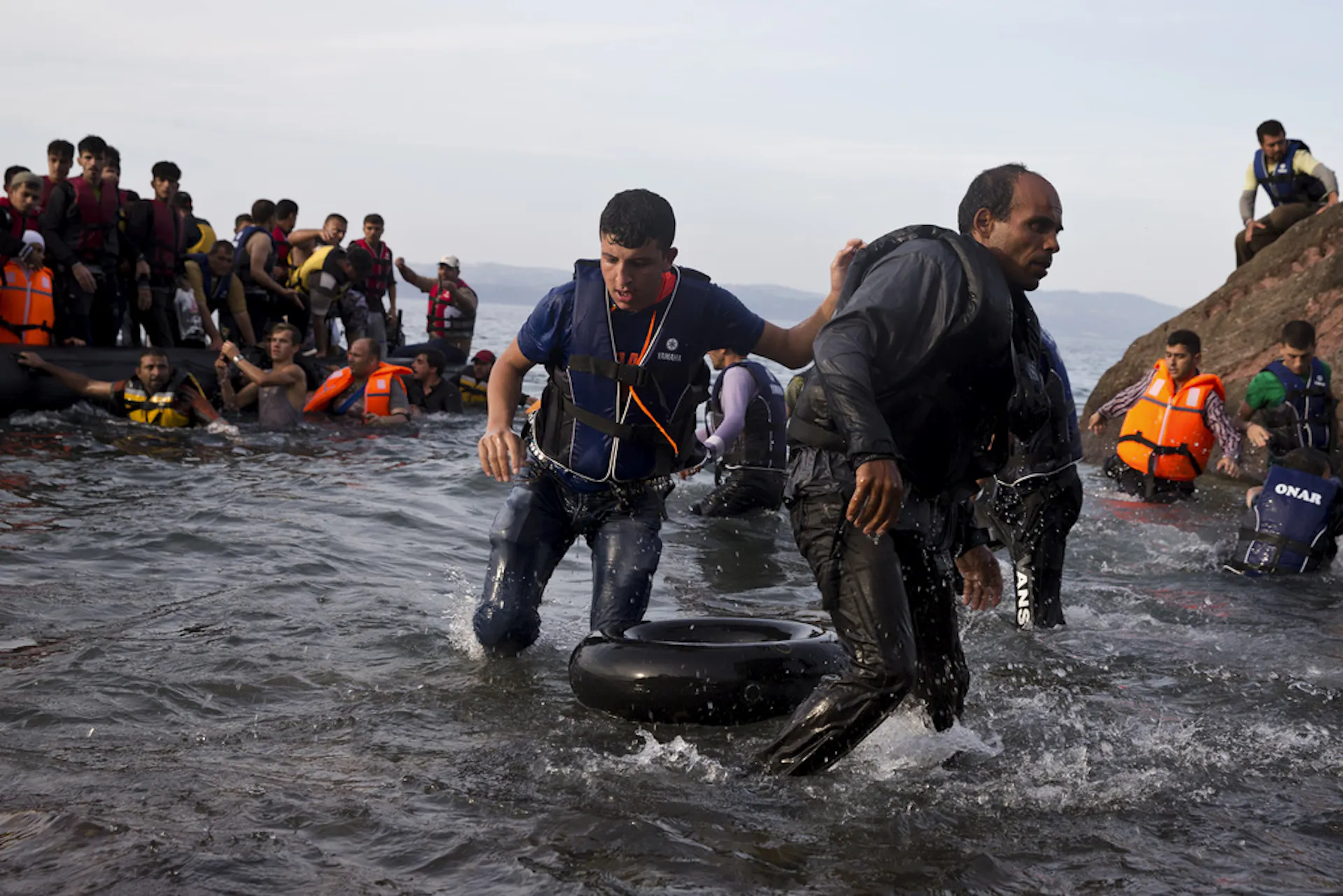 People walk onto a shore from makeshift boats.