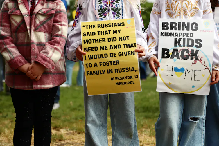 Protesters holding signs about Ukrainian children kidnapped by Russia.