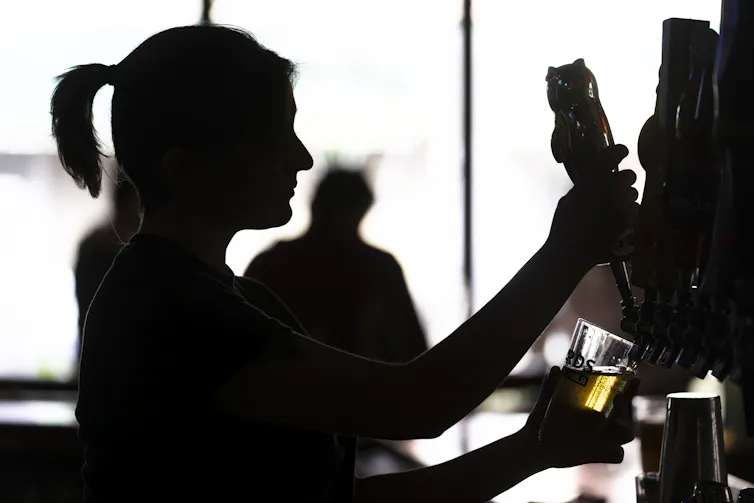 Silhouette of a bartender filling a glass with beer from a tap