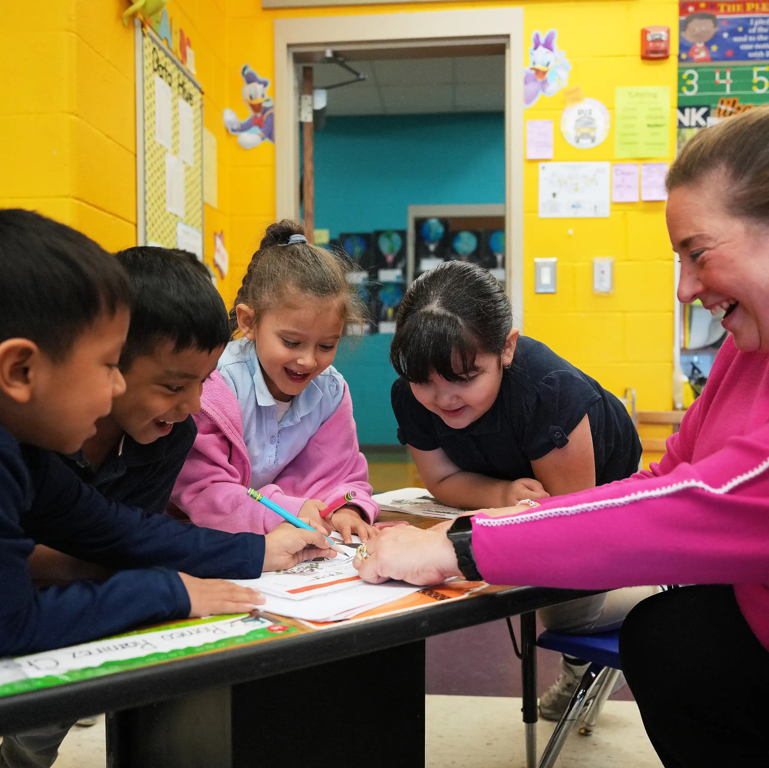 Teacher sits at desk with students