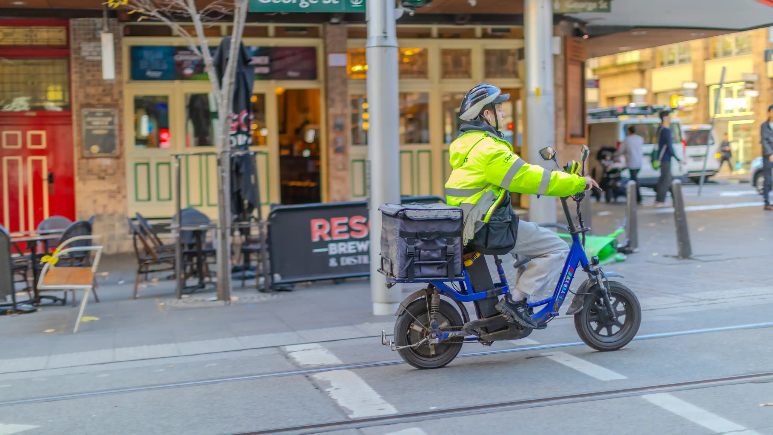 A food delivery rider, on a bicycle, rides along a street in Sydney