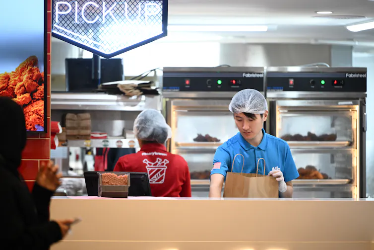 Fast food workers packing takeaway deliveries into paper bags.