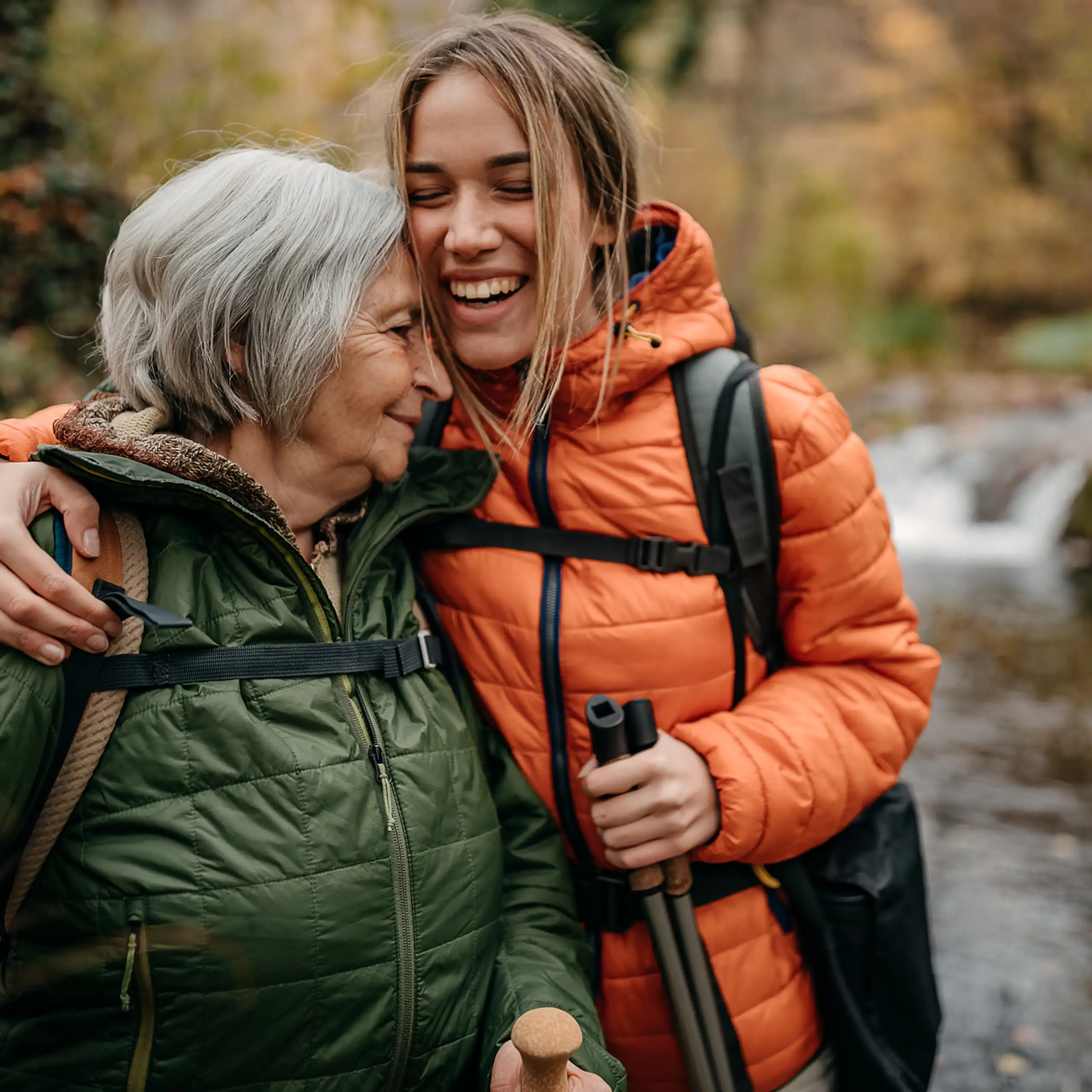 Older woman and younger woman hugging, on a hike