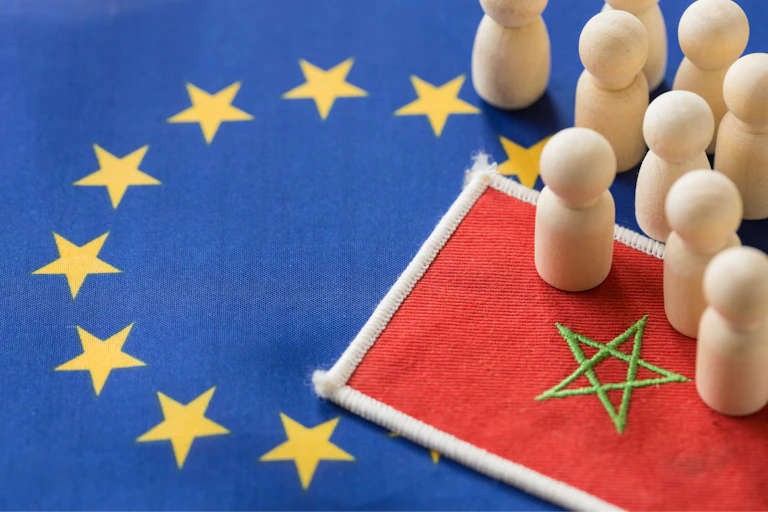 Piezas de madera sobre un tapete con las banderas de Marruecos y la UE.