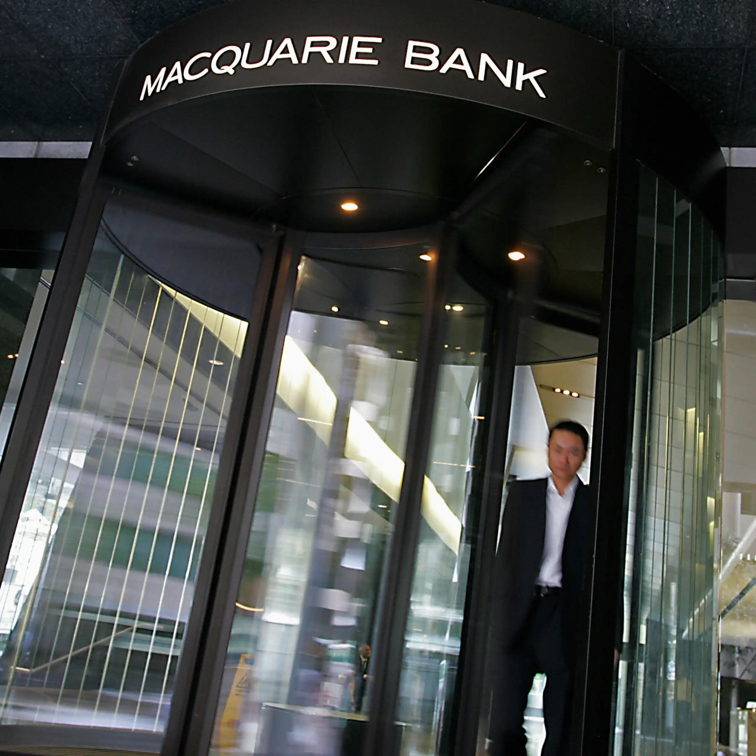 A man in a suit walking out of a Macquarie Bank