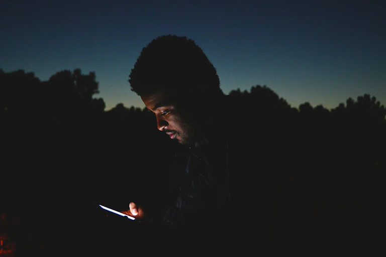 Un homme plongé dans la nuit utilise son portable.