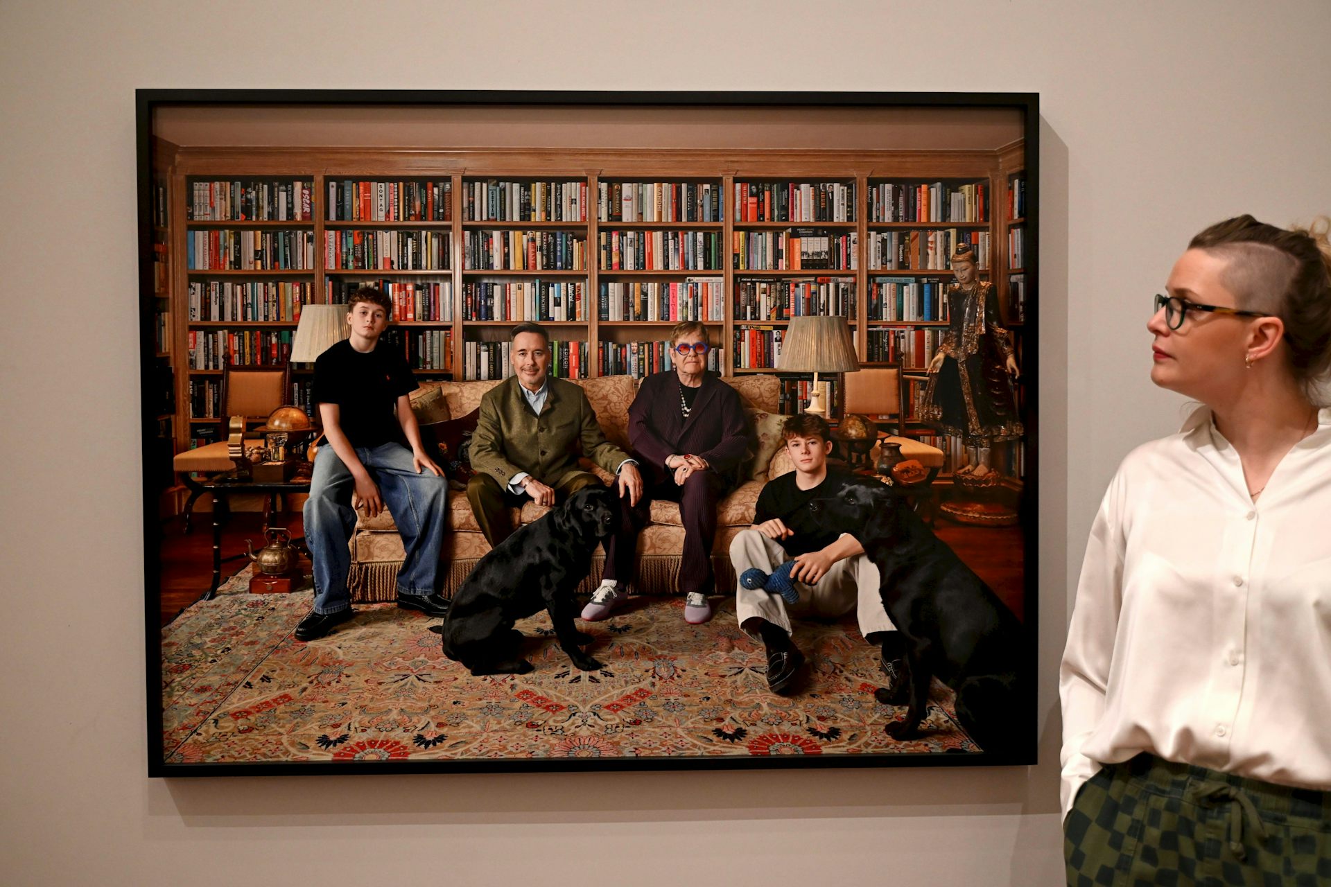 Two adult men and their teenage sons sitting on a sofa in a library.
