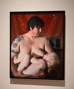 A photograph of a portrait of a woman breast-feeding her baby.